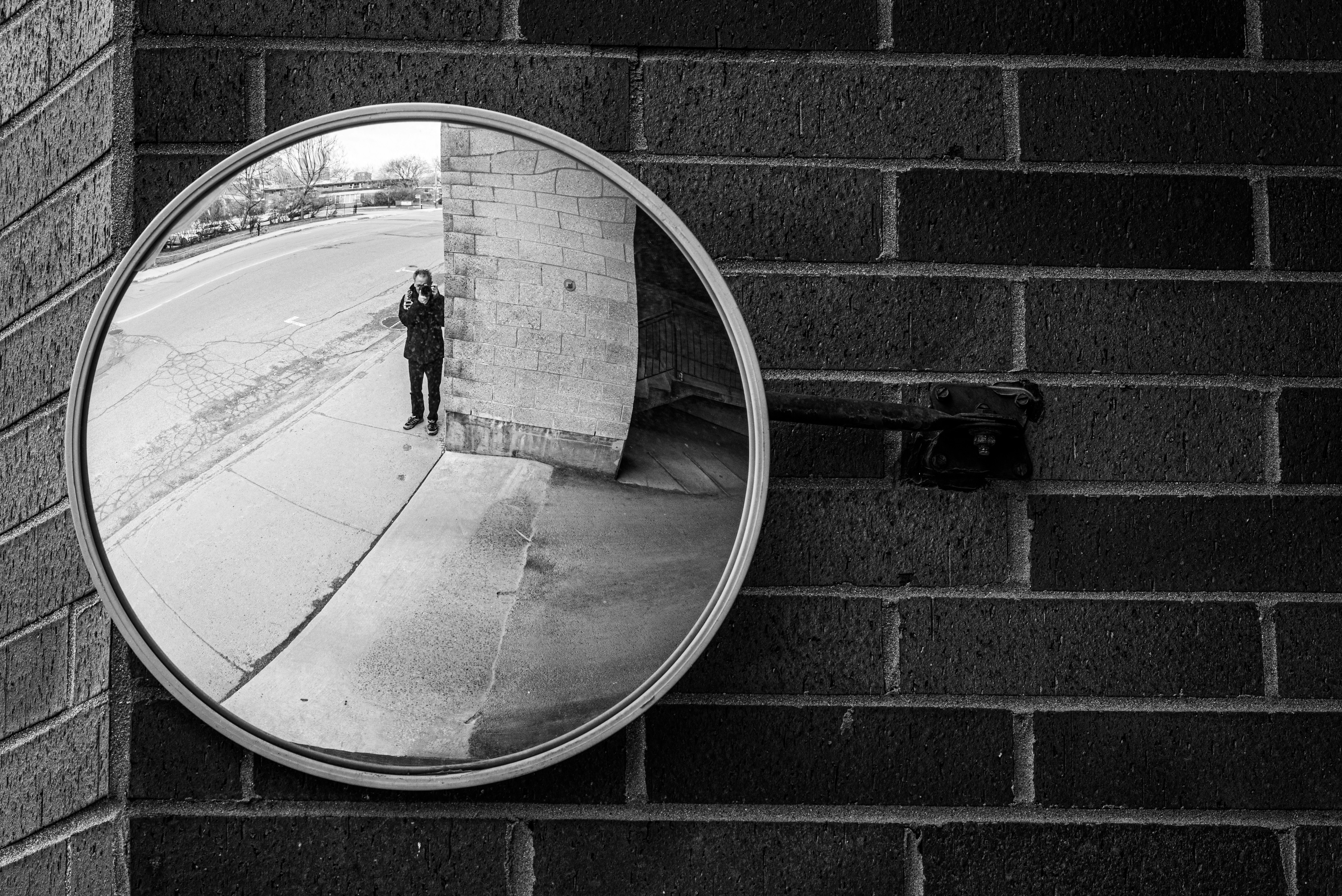 grayscale photo of man in black jacket and pants standing on basketball court
